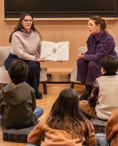 Two women reading tales in front of children
